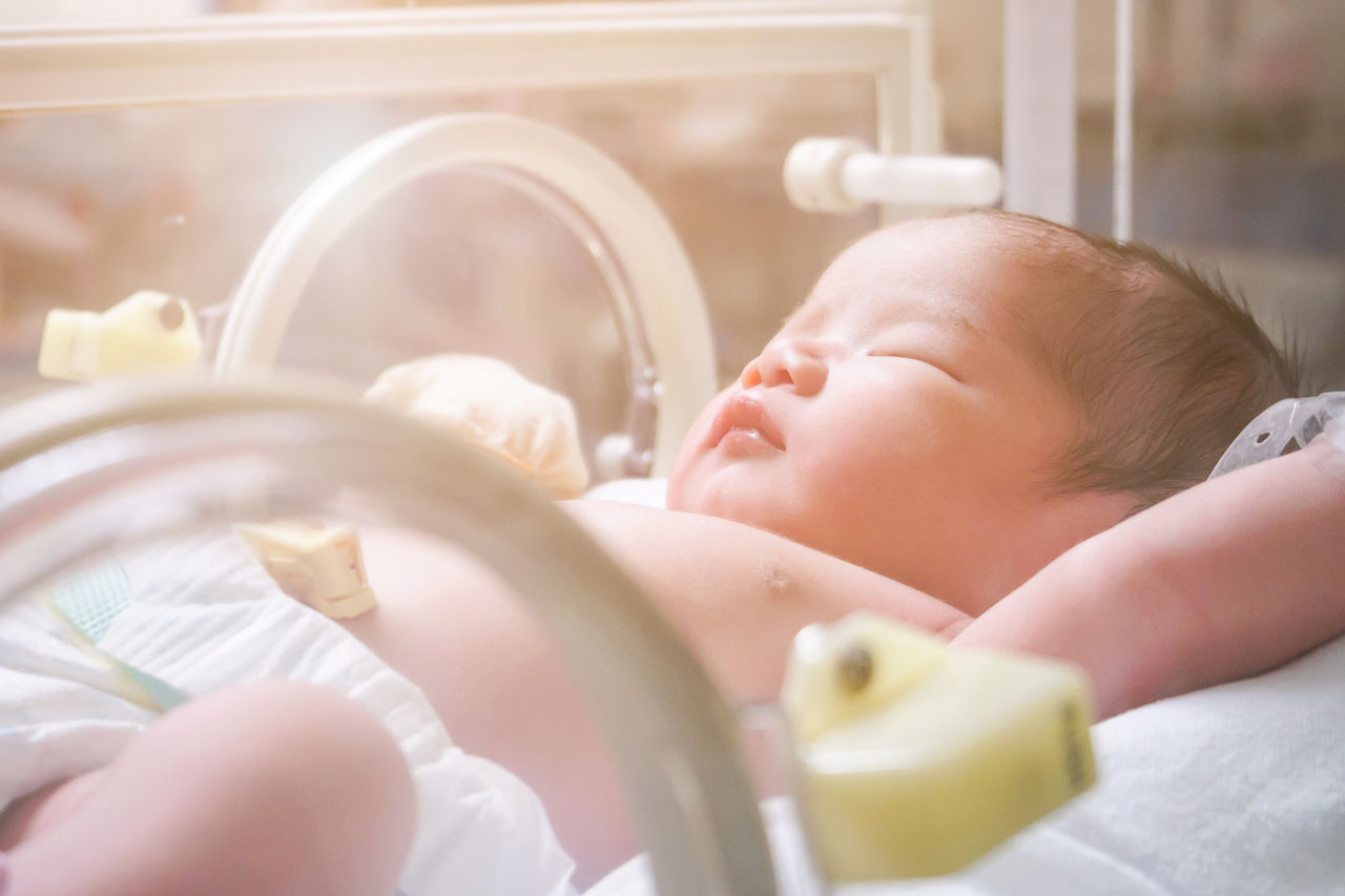 Newborn baby girl inside incubator in hospital post delivery room