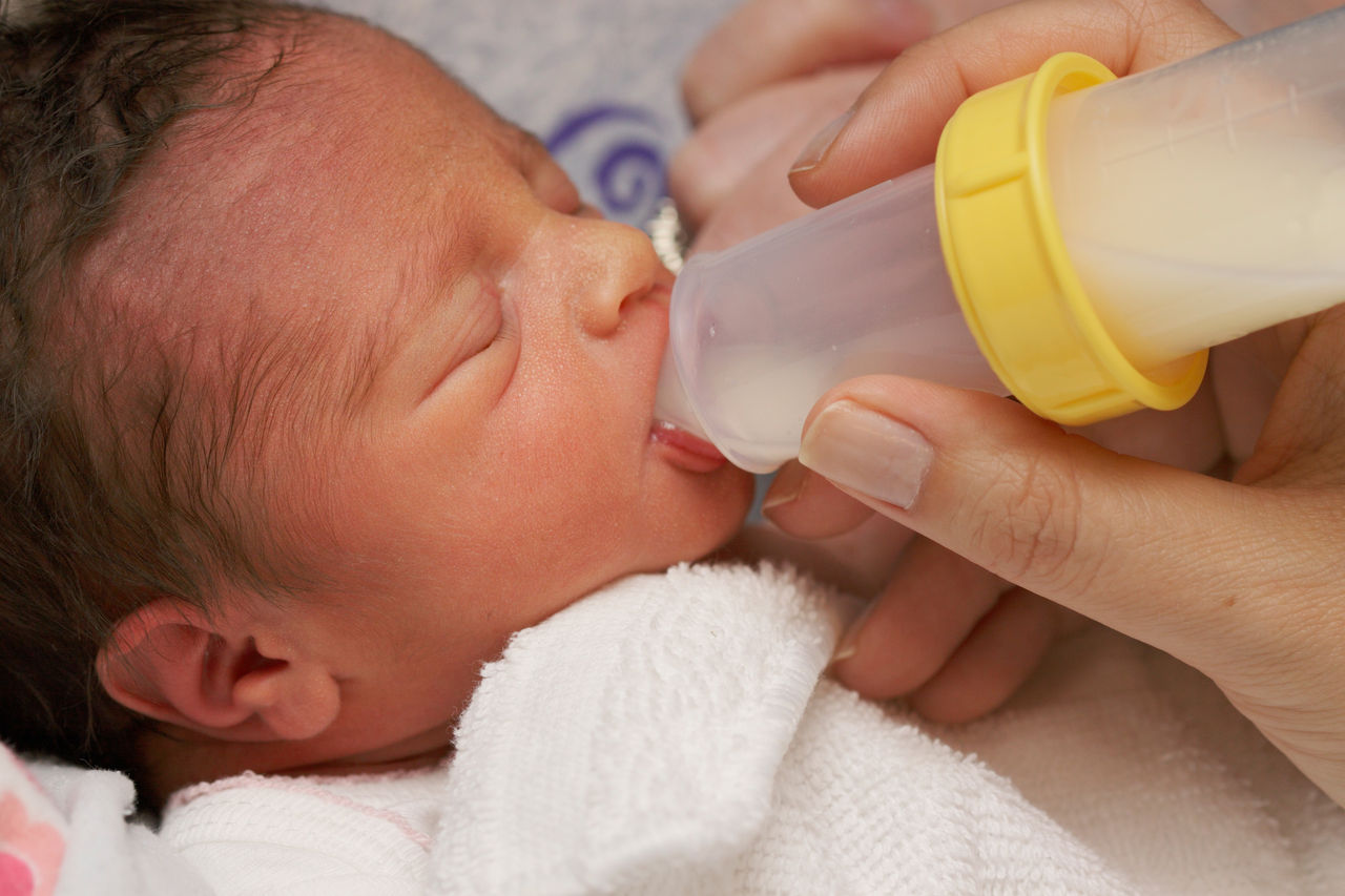 Closeup of premie drinking milk from a bottle.